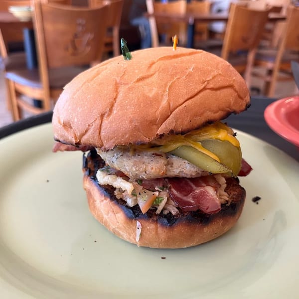 Lola's Chicken Shack fried chicken sandwich with bacon, pickles, and slaw on a toasted bun.