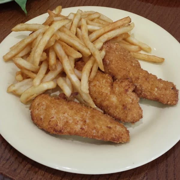 Three crispy fried chicken tenders and a pile of golden french fries on a white plate.