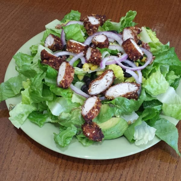 Lola's Chicken Shack salad with fried chicken, lettuce, red onion, corn, black beans, and avocado.