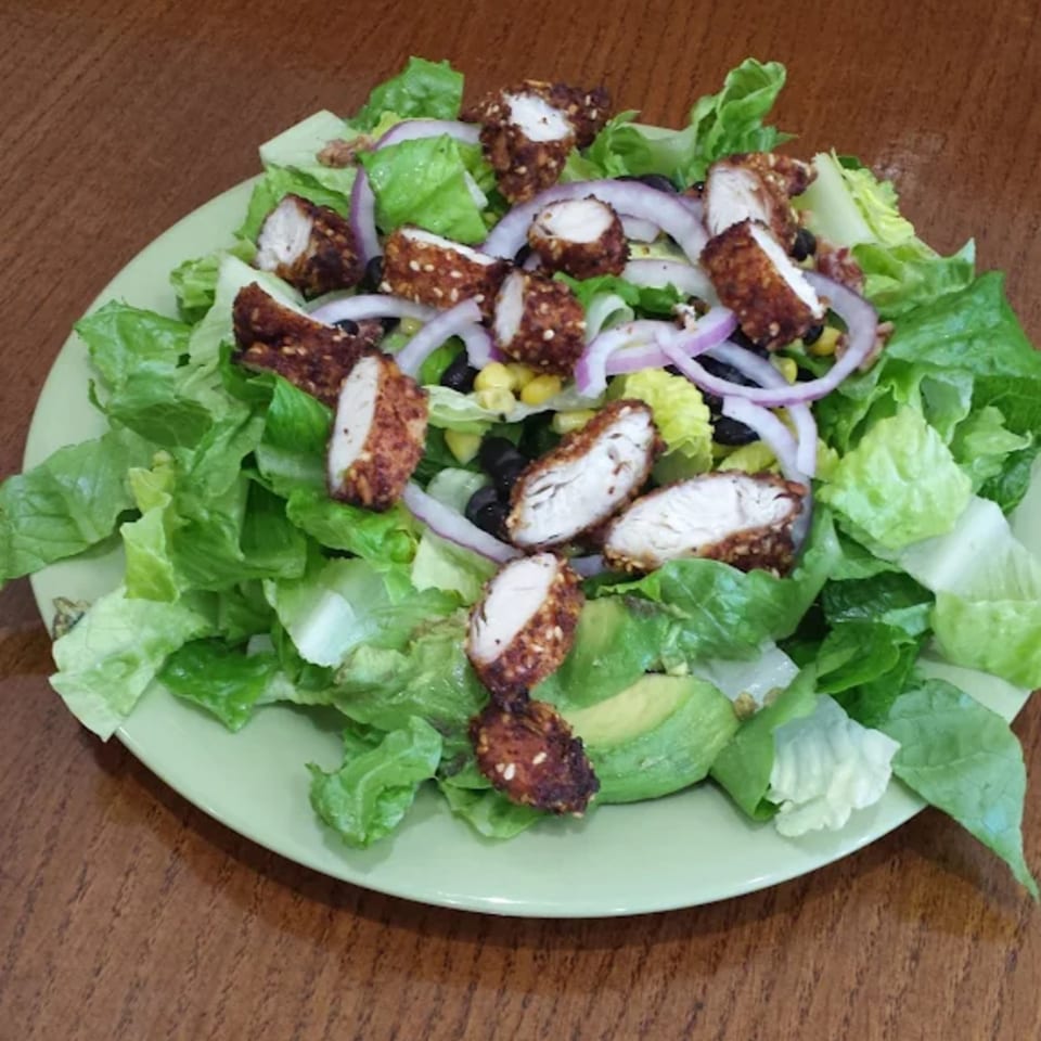 Lola's Chicken Shack salad with fried chicken, lettuce, red onion, corn, black beans, and avocado.